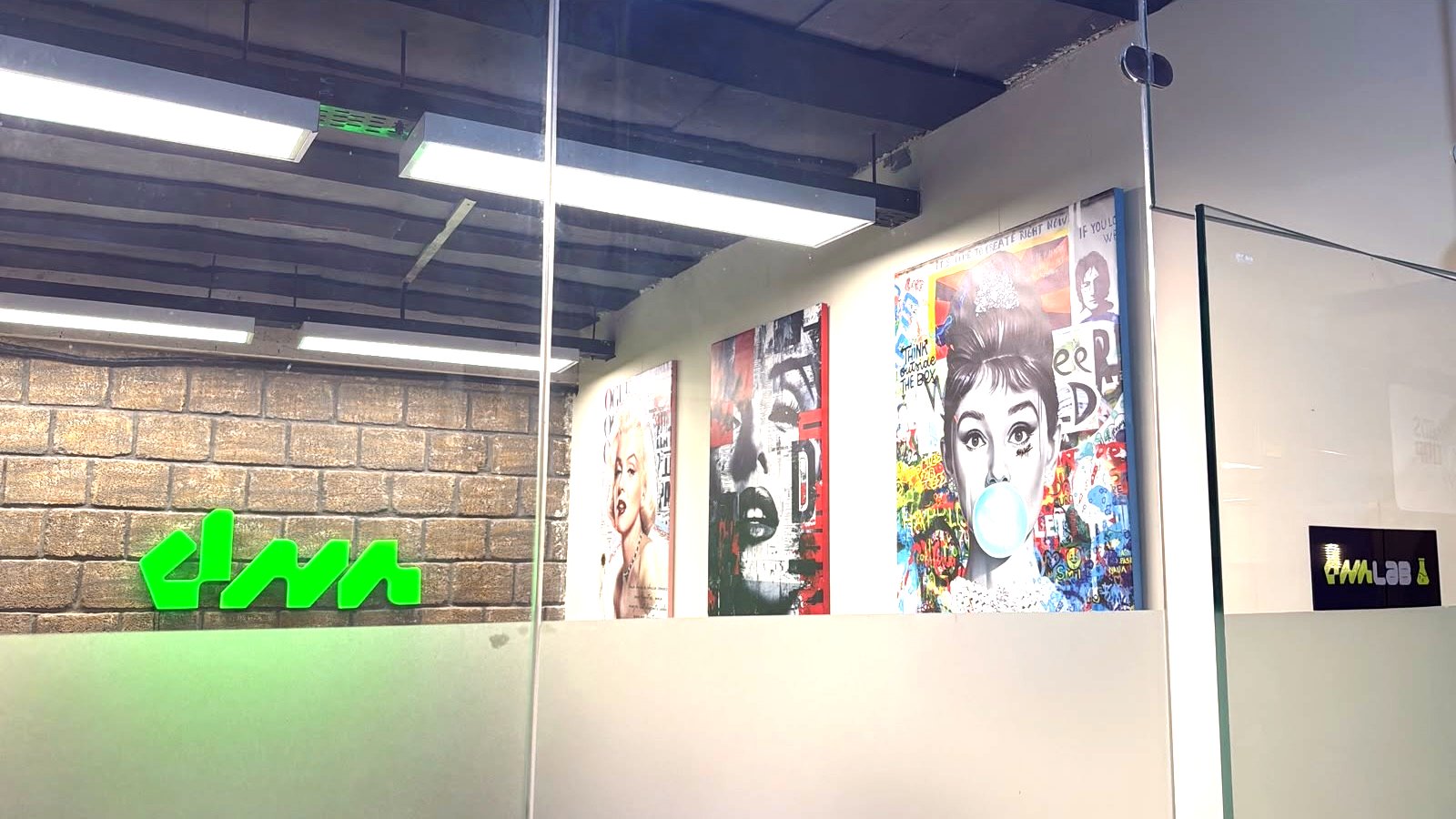 The DNA PR wall inside the BDS Corp head office — the illuminated dna mark beside the studio